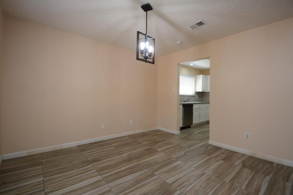 15 South Tallowberry Drive Spring, TX 77381 - Photo 4 of 26 Bright dining area with tile flooring, modern lighting, and an open layout leading to the kitchen with white cabinets and natural light.