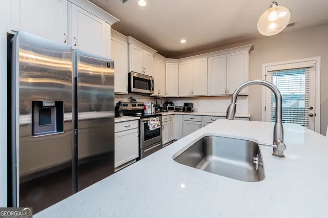 a kitchen with stainless steel appliances granite countertop a sink a stove and a refrigerator