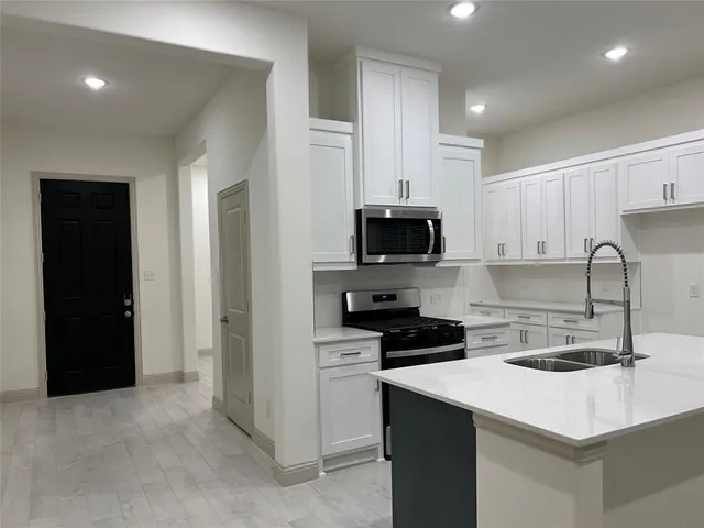 a large kitchen with stainless steel appliances kitchen island granite countertop a large counter top and a stove top oven