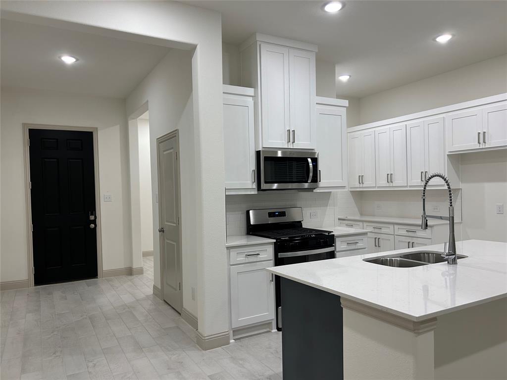 2905 Italia Terrace Princeton, TX 75407 - Photo 6 of 22 a kitchen with kitchen island a sink appliances and cabinets