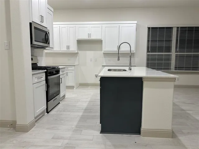 a kitchen with sink a microwave and cabinets