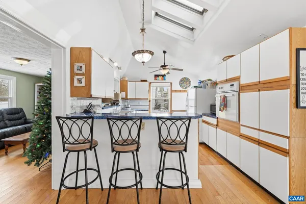 a kitchen with stainless steel appliances kitchen island granite countertop wooden floors and white cabinets