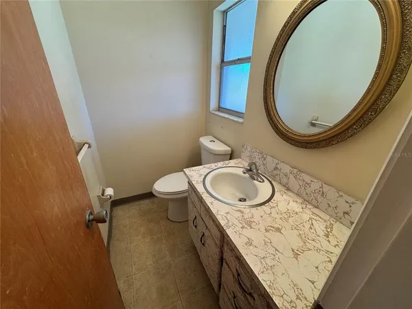 a bathroom with a granite countertop toilet sink mirror and window