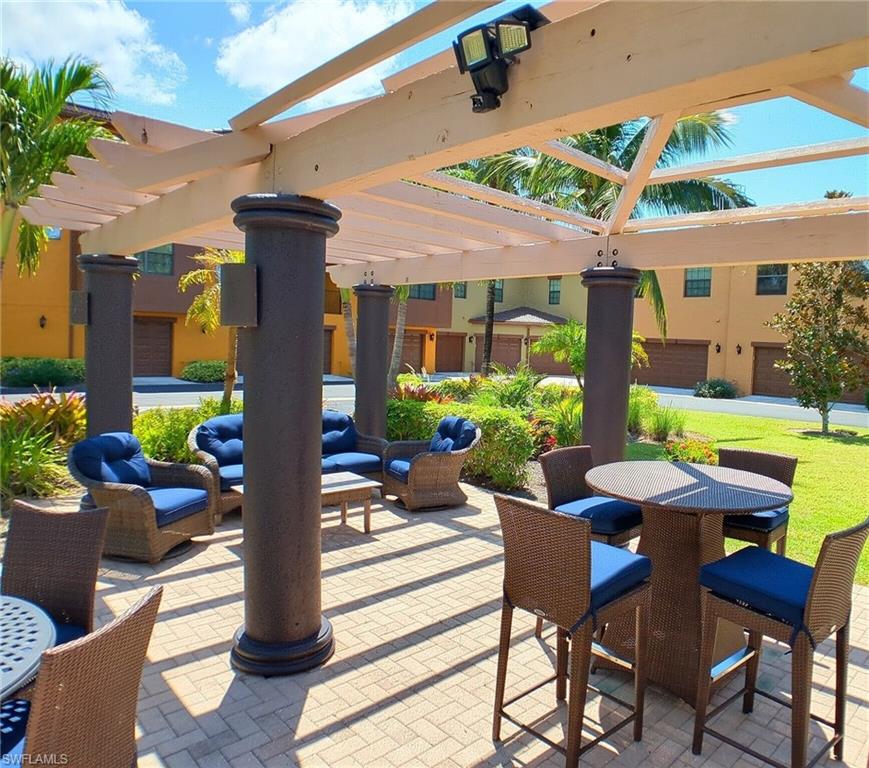 9055 Capistrano Street North, Unit 4206 Naples, FL 34113 - Photo 28 of 45 a view of a patio with a table and chairs under an umbrella