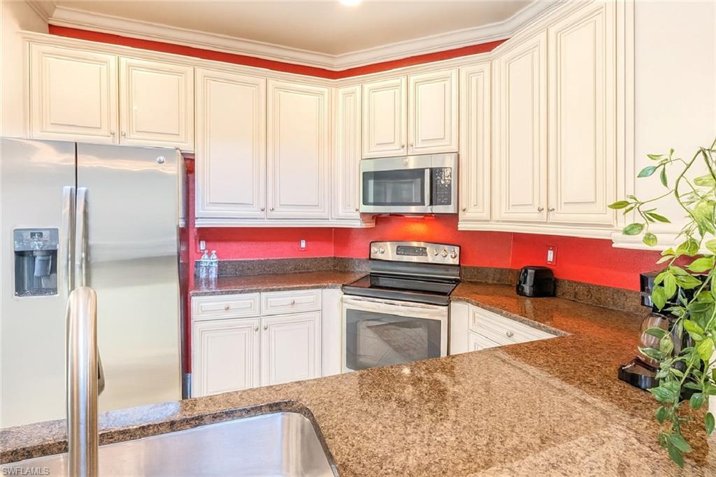 9055 Capistrano Street North, Unit 4206 Naples, FL 34113 - Photo 8 of 45 a kitchen with stainless steel appliances granite countertop a refrigerator a stove and white cabinets with wooden floor