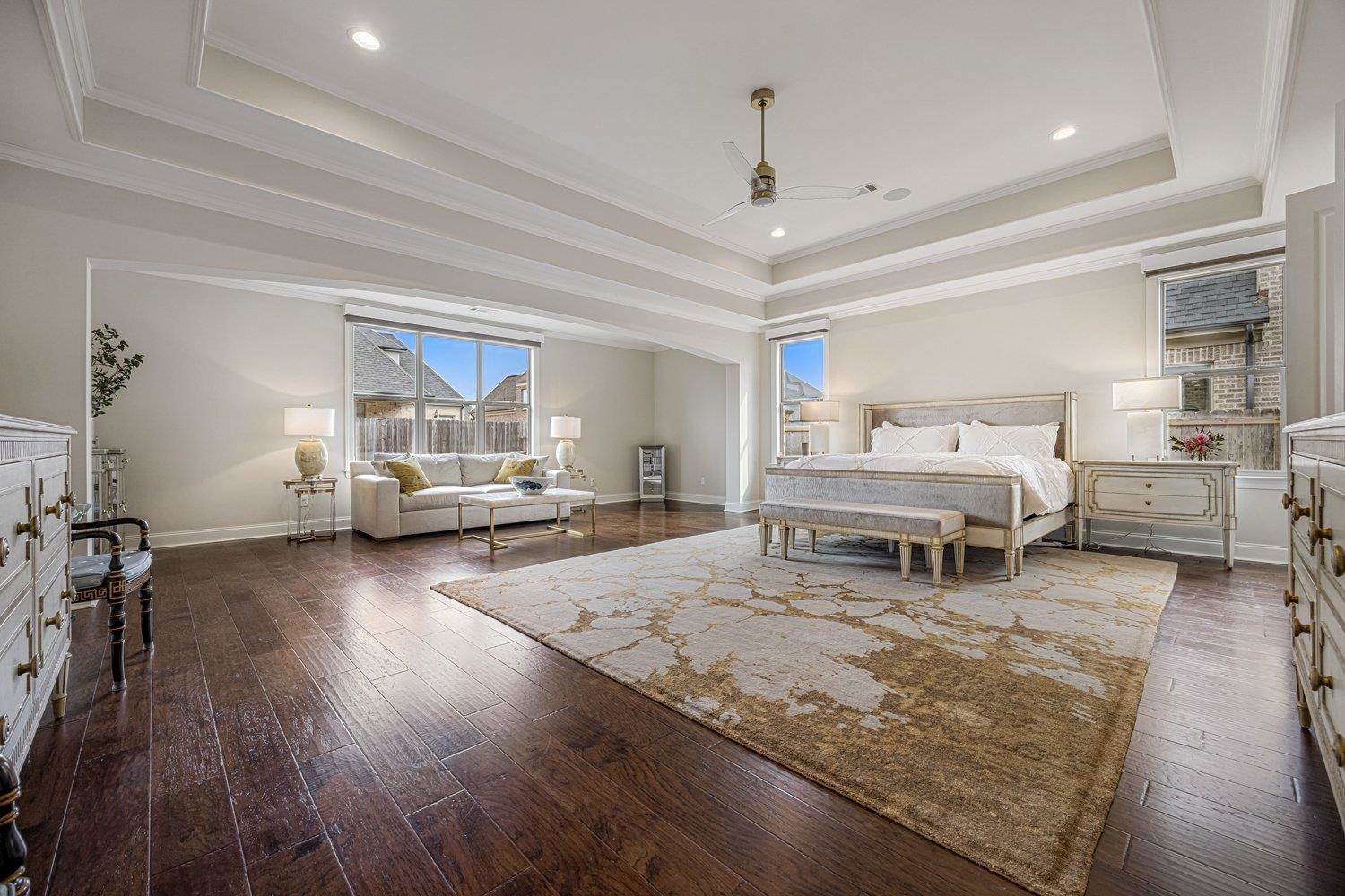 Bedroom with a tray ceiling, dark wood-style floors, ornamental molding, ceiling fan, and recessed lighting