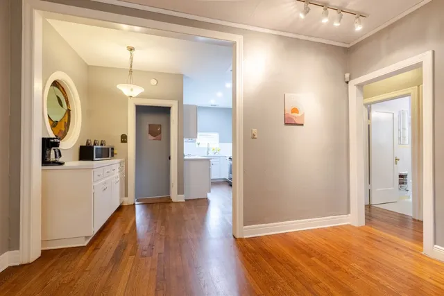 a view of a hallway with wooden floor and a bathroom