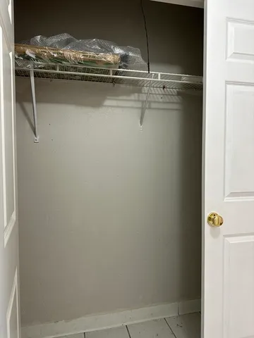 a view of an empty room with wooden floor and windows