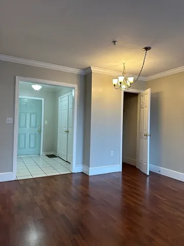 a view of a hallway with wooden floor and a bathroom