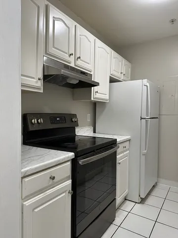a kitchen with stainless steel appliances granite countertop white cabinets and refrigerator