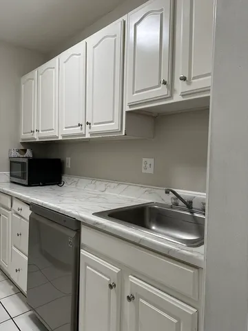 a kitchen with granite countertop white cabinets and a sink
