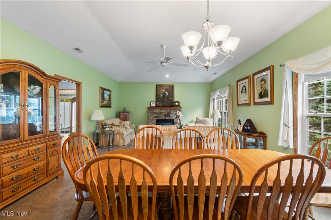 7030 Knight Avenue Northwest Canton, OH 44708 - Photo 11 of 26 Carpeted dining room with a stone fireplace and ceiling fan with notable chandelier
