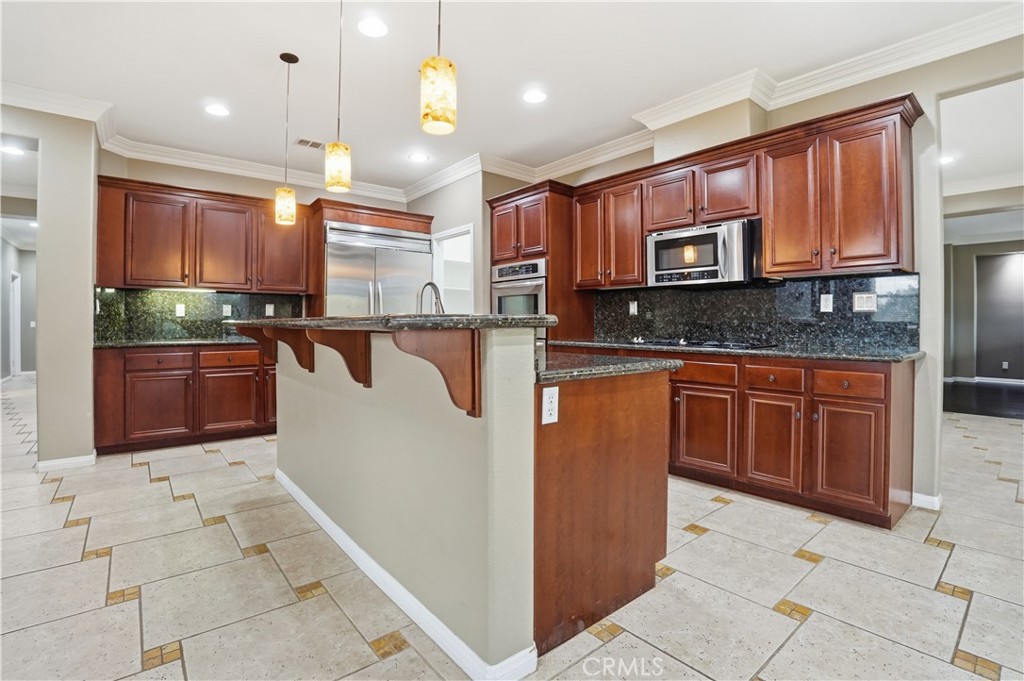 16935 Eagle Peak Road Riverside, CA 92504 - Photo 21 of 75 a kitchen with kitchen island granite countertop a stove top oven microwave and cabinets