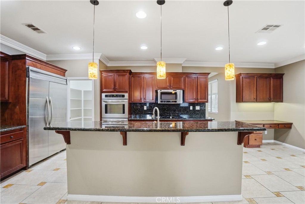 16935 Eagle Peak Road Riverside, CA 92504 - Photo 22 of 75 a kitchen with stainless steel appliances kitchen island granite countertop a sink a stove and a refrigerator