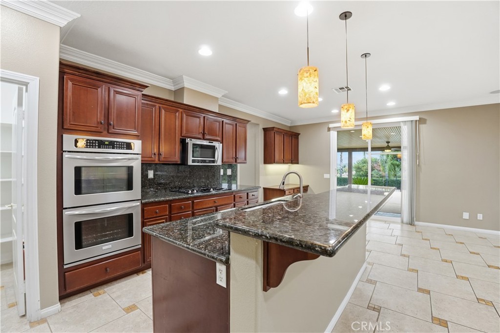 16935 Eagle Peak Road Riverside, CA 92504 - Photo 24 of 75 a kitchen with stainless steel appliances granite countertop a stove a refrigerator a sink a oven with a dining table and chairs