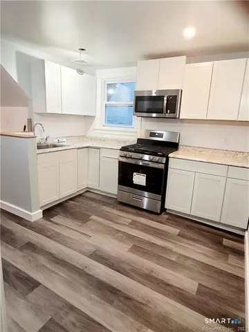 a kitchen with stainless steel appliances granite countertop a stove a sink and a microwave