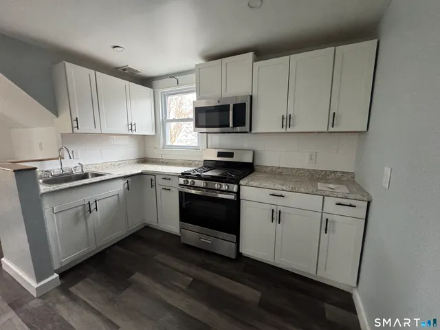 a kitchen with granite countertop white cabinets and white appliances