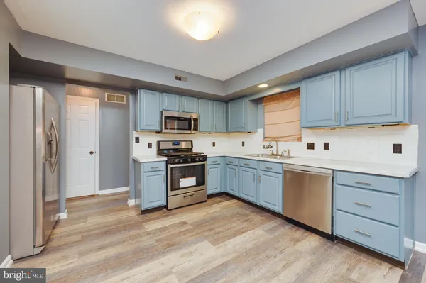a kitchen with granite countertop a sink cabinets stainless steel appliances and a window