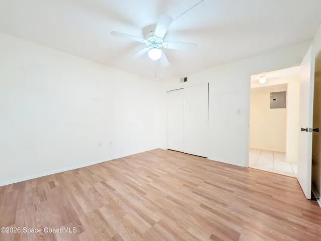 an empty room with wooden floor and fan