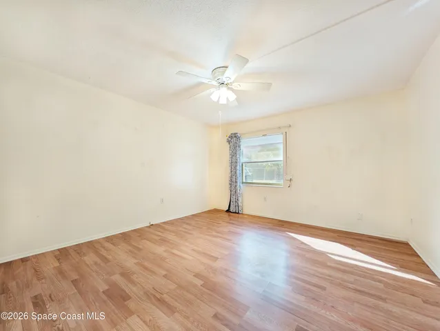 an empty room with a window and a ceiling fan