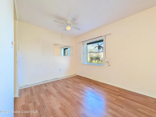 an empty room with wooden floor ceiling fan and windows