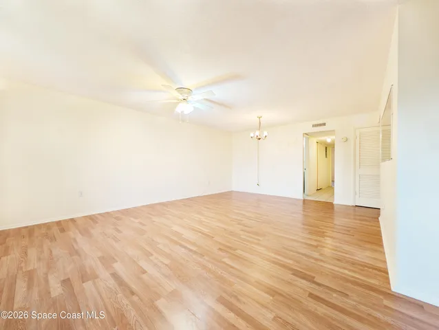 a view of empty room with wooden floor and fan
