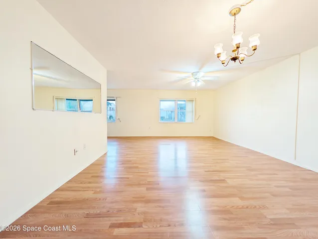 a view of an empty room with wooden floor and a chandelier