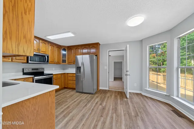 a kitchen with stainless steel appliances wooden floors and large window