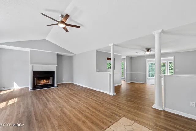a view of an empty room with wooden floor fireplace and a window
