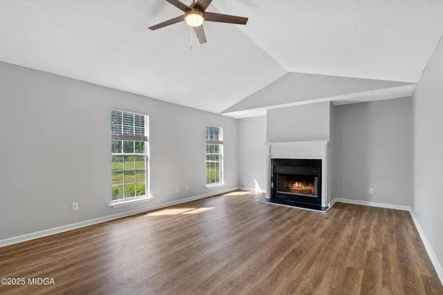 an empty room with windows a fireplace and wooden floor
