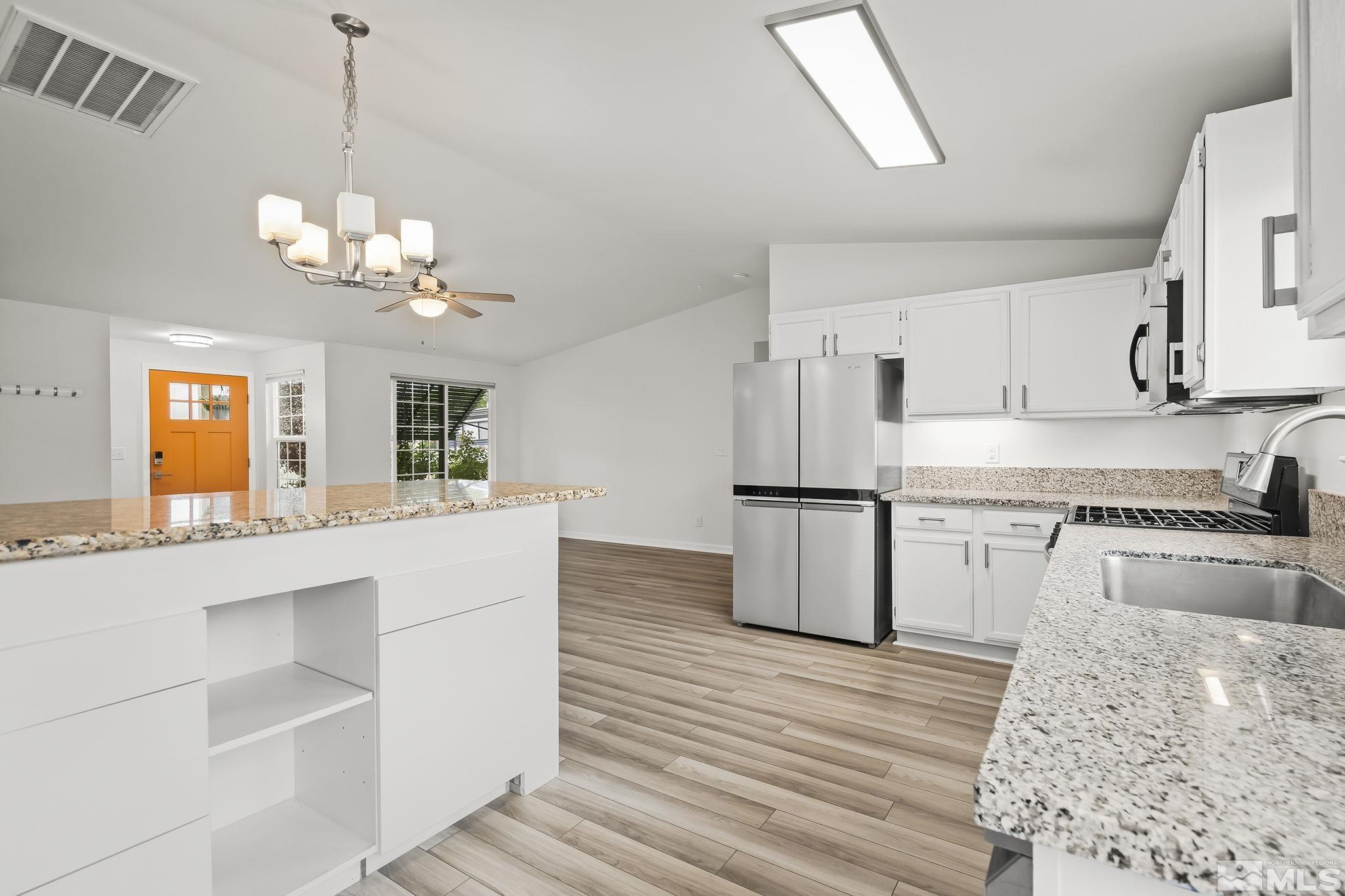 150 Rosecrest Drive Fernley, NV 89408 - Photo 11 of 28 a kitchen with kitchen island granite countertop wooden floors and stainless steel appliances