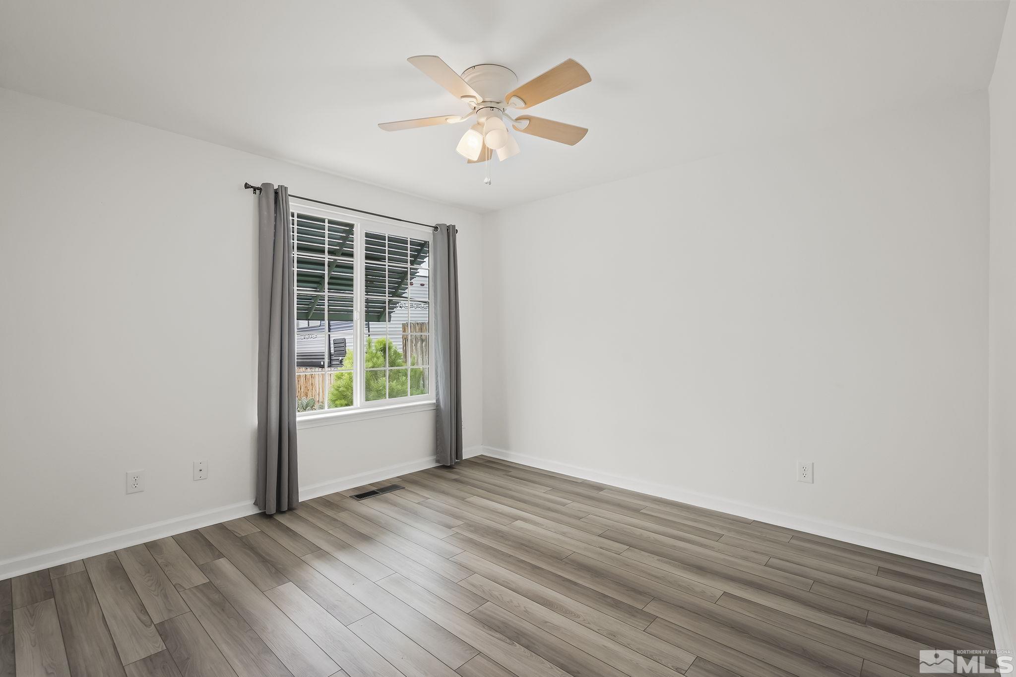 150 Rosecrest Drive Fernley, NV 89408 - Photo 17 of 28 an empty room with wooden floor and windows