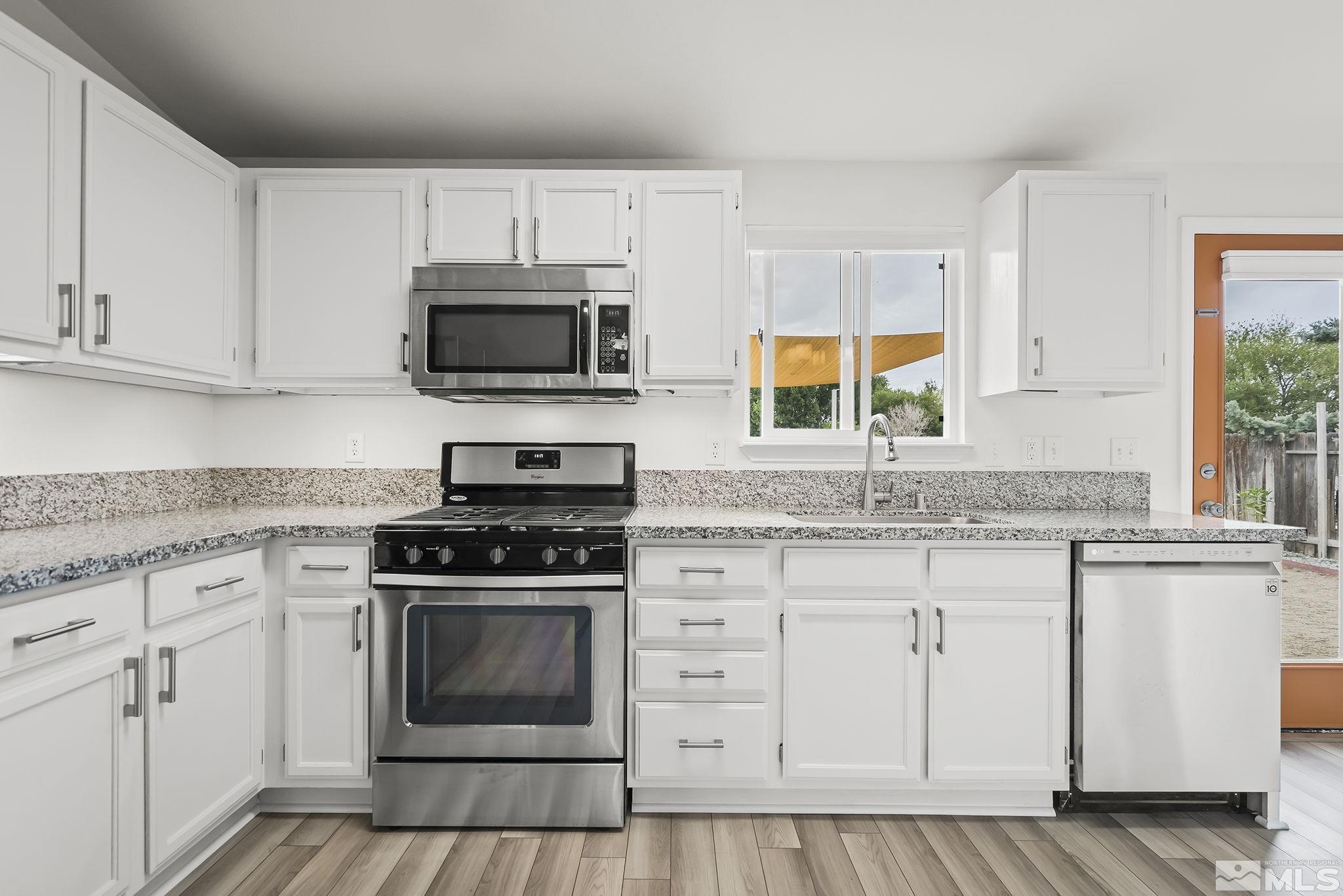150 Rosecrest Drive Fernley, NV 89408 - Photo 10 of 28 a kitchen with granite countertop white cabinets white stainless steel appliances and a sink