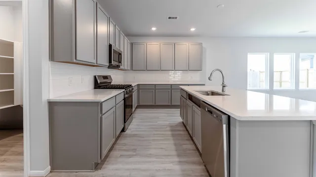 a kitchen with stainless steel appliances a sink stove cabinets and entryway