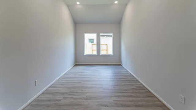 a view of an empty room with wooden floor and window