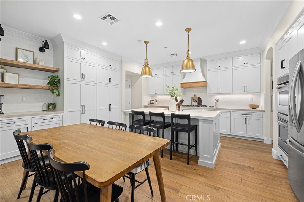18 Bower Lane Ladera Ranch, CA 92694 - Photo 3 of 31 a kitchen with stainless steel appliances kitchen island granite countertop a dining table chairs and white cabinets