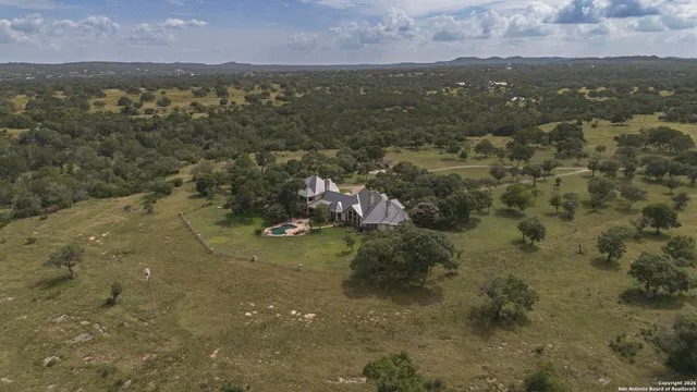 a view of a white house with a big yard and large trees