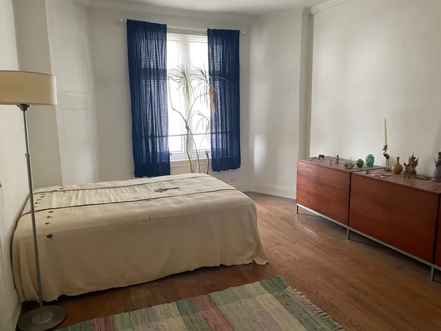 a spacious bedroom with a bed and wooden floor