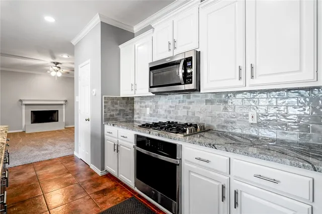 a kitchen with stainless steel appliances granite countertop grey cabinets a stove a sink and dishwasher