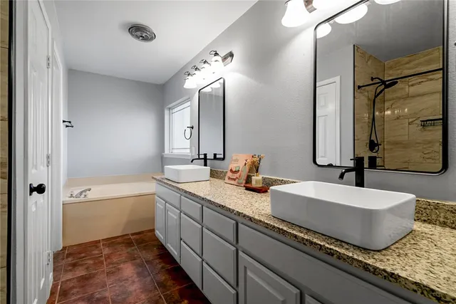 a bathroom with a granite countertop sink mirror and a bathtub