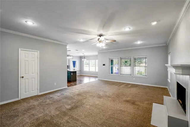 a view of a livingroom with a fireplace a ceiling fan and windows