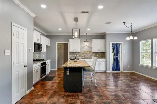 a large kitchen with a center island and stainless steel appliances