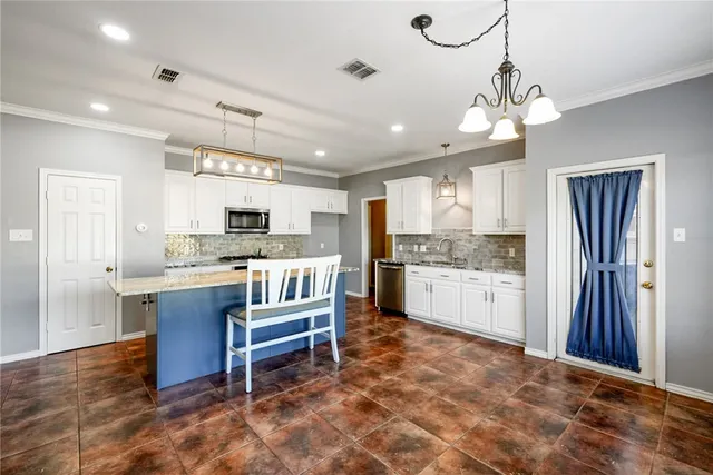 a large kitchen with kitchen island a large counter space a sink stainless steel appliances and cabinets