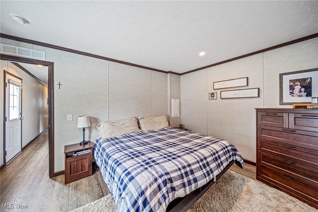 202 West Main Road, Unit LOT 13 Conneaut, OH 44030 - Photo 20 of 23 Bedroom with ornamental molding, light wood-type flooring, and a textured ceiling
