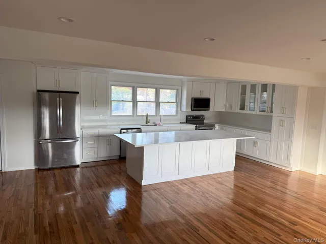 a kitchen with stainless steel appliances granite countertop a refrigerator a stove top oven a sink dishwasher and wooden floor