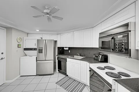 a kitchen with a refrigerator a stove a sink and white cabinets