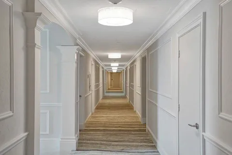 a view of a hallway with wooden floor and chandelier