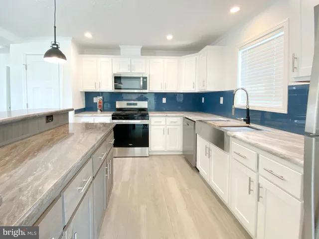 a large kitchen with stainless steel appliances granite countertop a sink and a stove