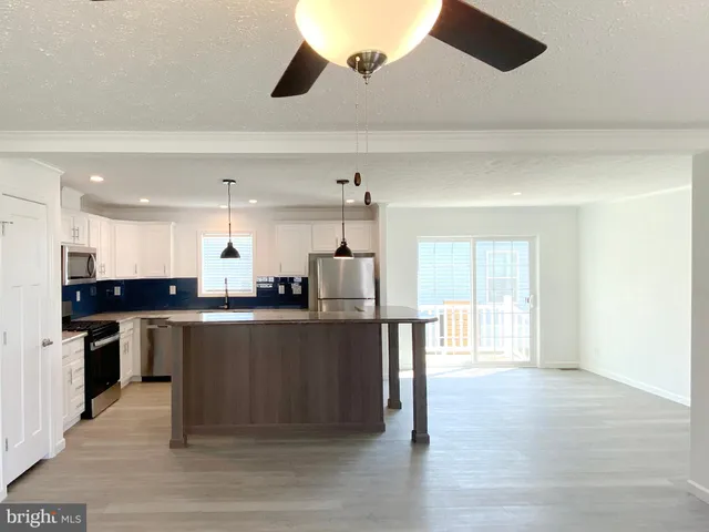 a kitchen with kitchen island granite countertop a stove top oven a sink a counter space and cabinets