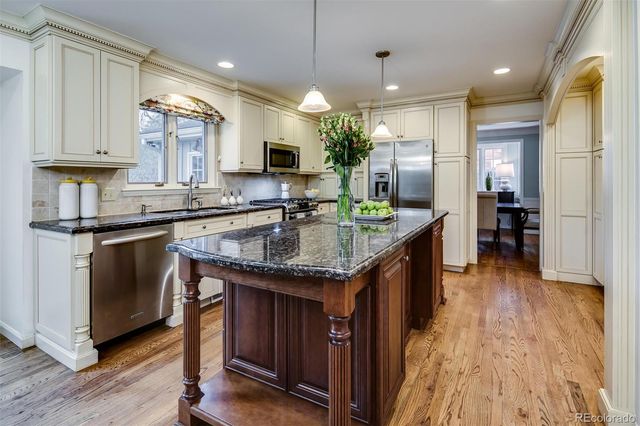 a kitchen with stainless steel appliances granite countertop a sink a stove and a wooden floors